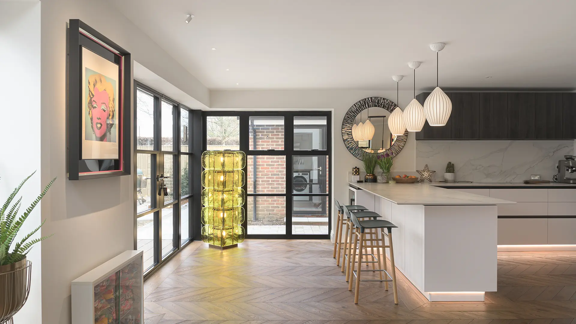 Contemporary lighting frames the space between the kitchen and outdoor entertainment space